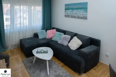 a living room with a black couch with colorful pillows at Perla Lux Apartments in Arandjelovac