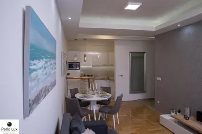 a kitchen and a living room with a table and chairs at Perla Lux Apartments in Arandjelovac