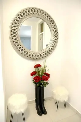 a mirror on a wall with a vase with red flowers at Apartment A in Belgrade