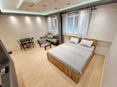 a bedroom with a bed and a couch and a table at Apartmani Paku in Belgrade
