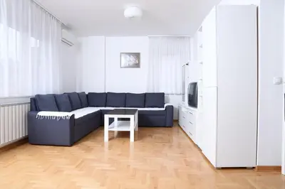 a living room with a blue couch and a table at Zap apartman in Belgrade