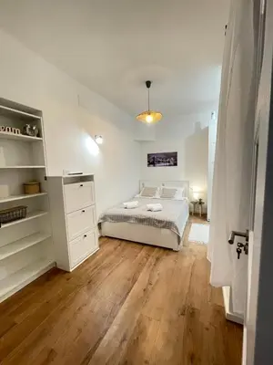 a white bedroom with a bed and a wooden floor at Apartment 42 - City Center in Belgrade