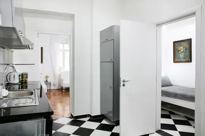 a kitchen with a refrigerator and a black and white checkered floor at Natalie's Home in Belgrade