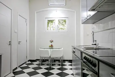 a white kitchen with a black and white checkered floor at Natalie's Home in Belgrade