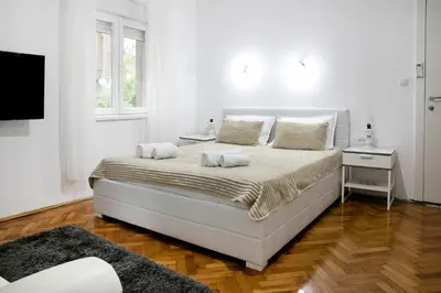 a white bedroom with a large bed with two pillows at Natalie's Home in Belgrade