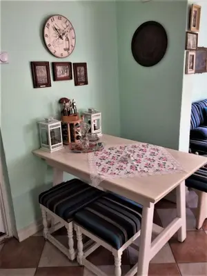 a table with two chairs and a clock on the wall at Šumska kuća Sandy in Banatski Karlovac