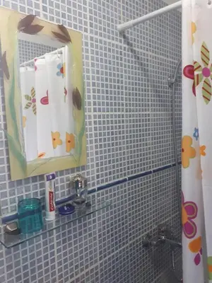 a white tiled bathroom with a mirror and a sink at Šumska kuća Sandy in Banatski Karlovac