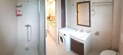 a bathroom with a shower and a sink and a washing machine at Apartments Exclusive in Belgrade