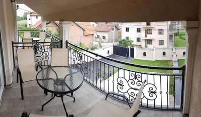 a balcony with a table and a view of a yard at Apartments Exclusive in Belgrade