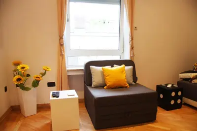 a chair with a yellow pillow in a room with a window at St. Marko Church App in Belgrade