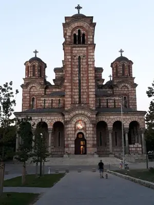 a man walking a dog in front of a church at St. Marko Church App in Belgrade