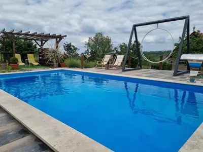 a blue swimming pool with a swing and a table at Vila Stancevic wellness in Sremski Karlovci