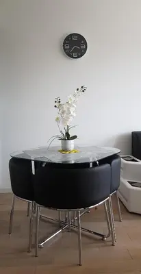 a table with two black chairs and a vase with flowers on it at Spa Panorama in Belgrade