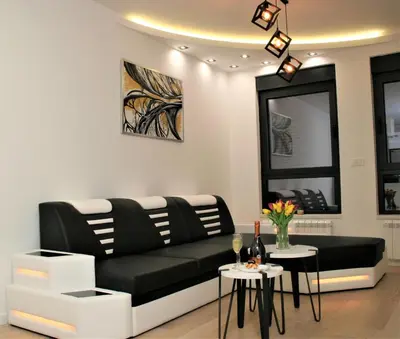 a living room with a black couch and two tables at Spa Panorama in Belgrade