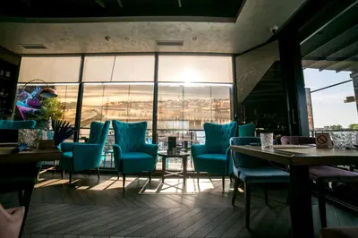 a restaurant with blue chairs and tables and windows at FLOW in Belgrade