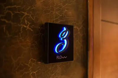 a lightswitch with a blue neon sign on a wall at FLOW in Belgrade
