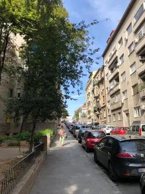 a person walking down a street next to parked cars at Tulum Apart Belgrade in Belgrade