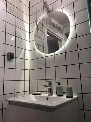 a white tiled bathroom with a sink and a mirror at Tulum Apart Belgrade in Belgrade