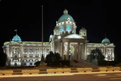 a large white building with a tower at night at Viktor Luxury Suites in Belgrade