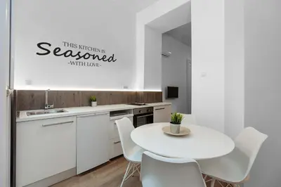 a white kitchen with a white table and chairs at Viktor Luxury Suites in Belgrade