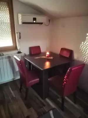 a dining room table with red chairs and a candle on it at Apartment Viktor in Belgrade