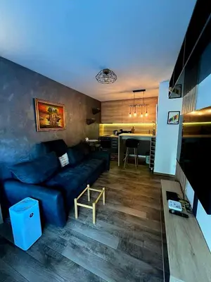 a living room with a blue couch and a kitchen at LUX Apartment A&M Netflix in Belgrade
