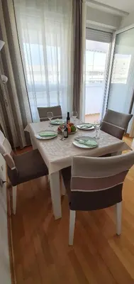 a dining room table with chairs and a white table with glasses at Royal apartment Belvill in Belgrade
