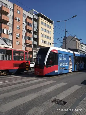 a red white and blue train on a city street at Vlado apartment VS in Belgrade