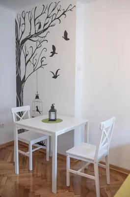 a dining room table with birds and a tree mural at Sweet Home in Belgrade