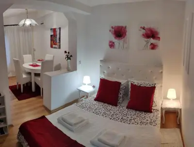 a bedroom with a bed with red pillows and a table at Gardos dupleks in Belgrade