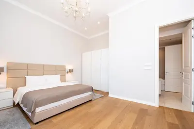 a white bedroom with a bed and a chandelier at Slavija Fontana Lux Apartments in Belgrade