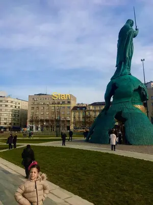 a little girl standing in front of a statue at Savski Square Suites in Sajmište