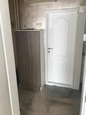 a hallway with a white door and a wooden cabinet at Savski Square Suites in Sajmište