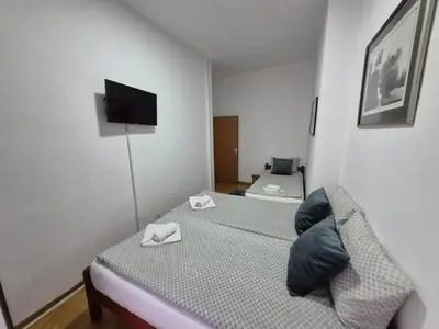 a small bedroom with two beds and a flat screen tv at Authentic Belgrade Centre Apartment #2, Four Bedrooms, One full Bathroom, One Toilet in Belgrade