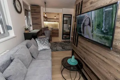 a living room with a couch and a tv on a wall at Apartment Story,Nikole Cupica Beograd in Belgrade