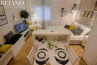 a small living room with a white bed and a table at Studio Stil in Belgrade