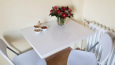 a white table with a vase of flowers and two chairs at Bella Vita Apartment in Belgrade
