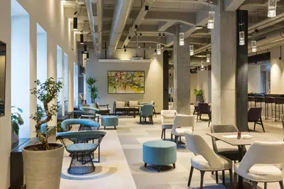 a lobby with tables and chairs in a building at Hotel Mona Plaza in Belgrade