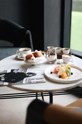 a table with a plate of food and cups of coffee at Hotel Mona Plaza in Belgrade