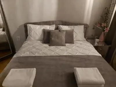 a large bed with two pillows and two tables on it at Apartment De Luna Belgrade in Belgrade