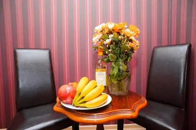 a table with a plate of fruit and a vase of flowers at Villa Bulevar in Belgrade