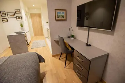 a bedroom with a desk with a television on the wall at Belgrade Waterfront GREEN Apartment in Belgrade