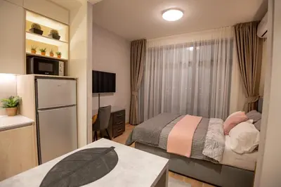 a small bedroom with a bed and a refrigerator at Belgrade Waterfront GREEN Apartment in Belgrade