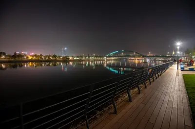 a boardwalk next to a body of water at night at Belgrade Waterfront GREEN Apartment in Belgrade