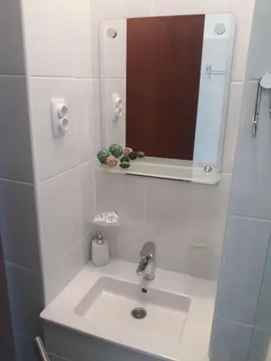 a white bathroom with a sink and a mirror at Apartman Karadjordje in Zvezdara
