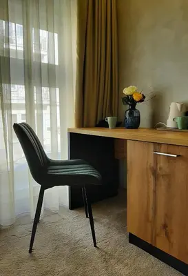 a black chair sitting next to a desk with a vase of flowers at Urban Lodge Belgrade in Belgrade