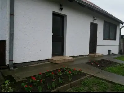 a white house with a door and some flowers at Apartman Sissi in Pančevo