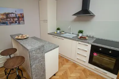 a kitchen with white cabinets and a counter with stools at Vracar Vuk 2 in Belgrade