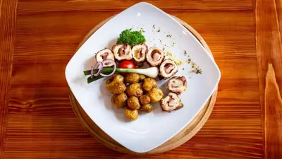 a white plate with food on a wooden table at Hotel Kutko in Pančevo