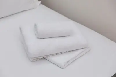 a stack of white towels sitting on a bed at Hotel Kutko in Pančevo